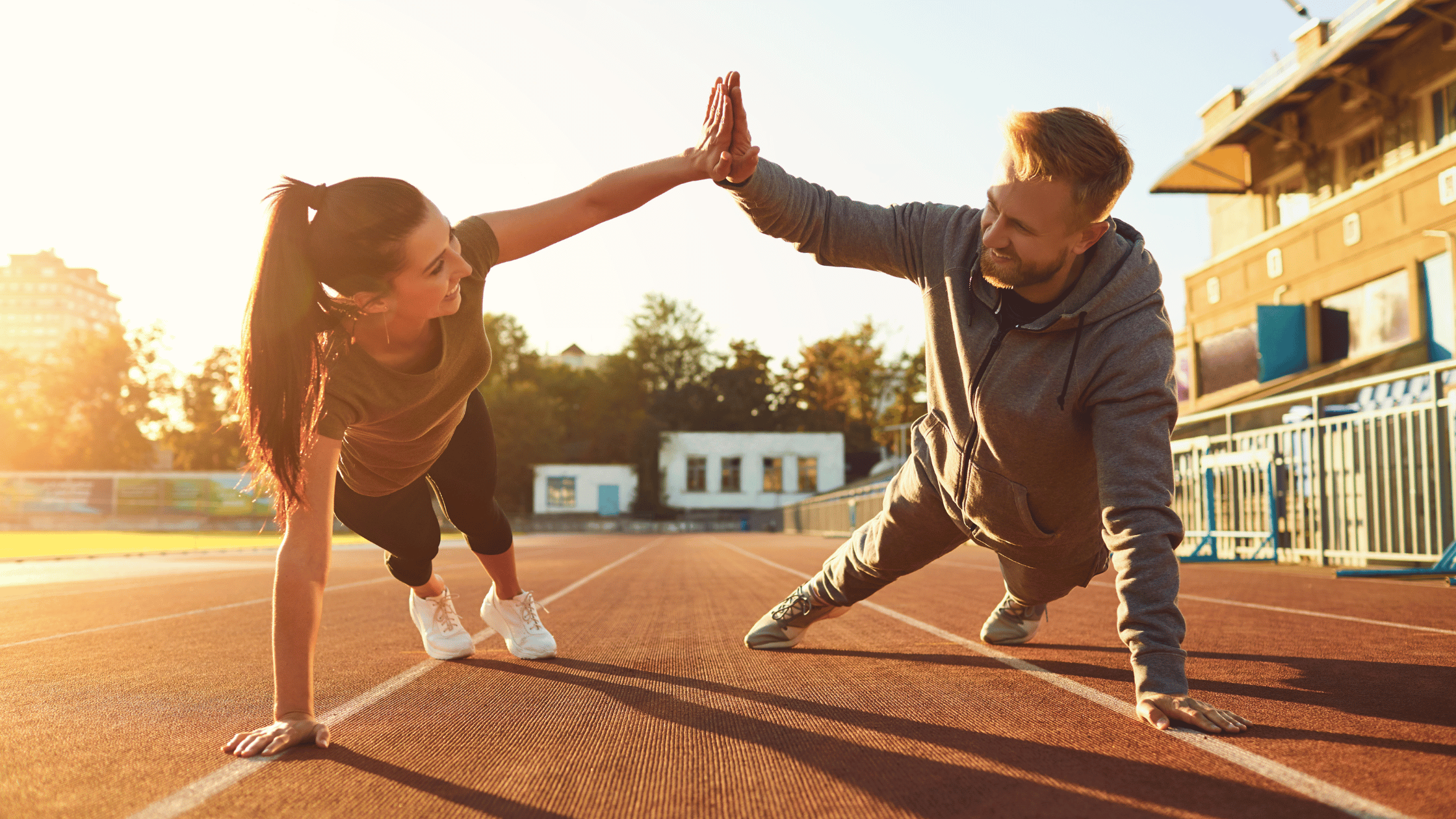 Two women high-fiving outdoors during exercise, symbolizing energy and vitality affected by cortisol and testosterone balance in women