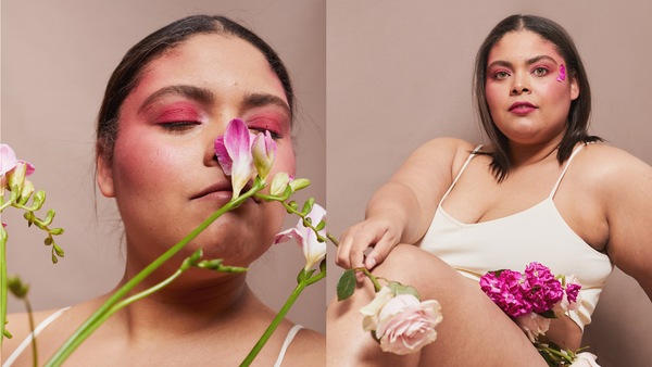 woman smelling flowTwo confident women with bold pink makeup posing with flowers, representing feminine wellness and the hormonal imbalance of estrogen dominanceers modeling