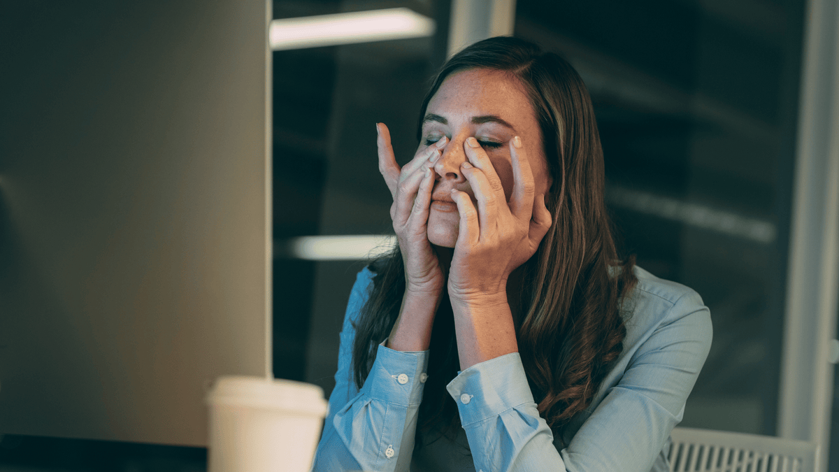 Woman covering her face with both hands looking overwhelmed and exhausted, illustrating the wired-but-tired feeling caused by chronically elevated cortisol levels
