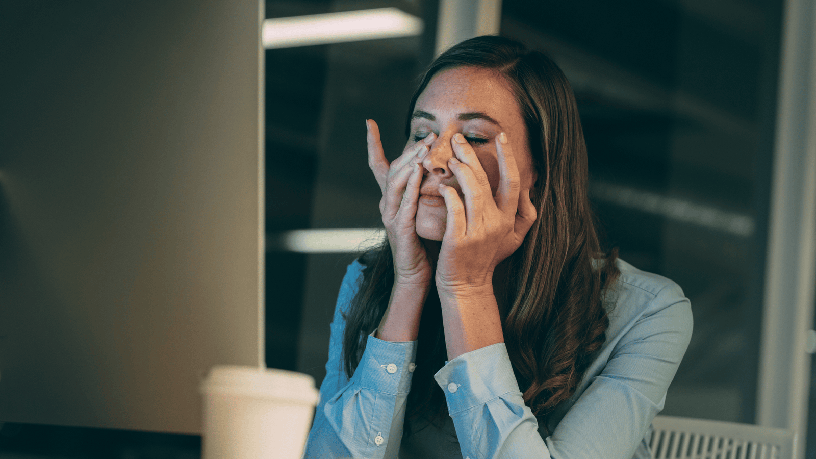 Woman covering her face with both hands looking overwhelmed and exhausted, illustrating the wired-but-tired feeling caused by chronically elevated cortisol levels