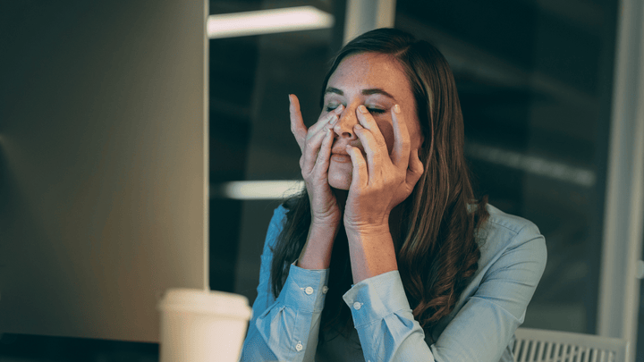 Woman covering her face with both hands looking overwhelmed and exhausted, illustrating the wired-but-tired feeling caused by chronically elevated cortisol levels